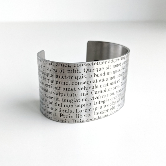 Wide silver tone cuff with Latin script